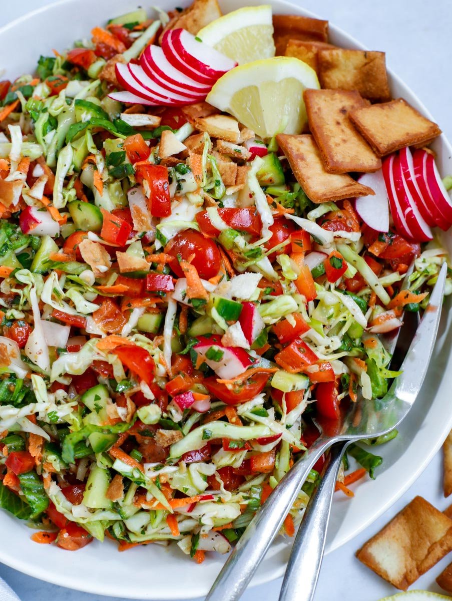 Cabbage fattoush salad in a bowl with serving spoons