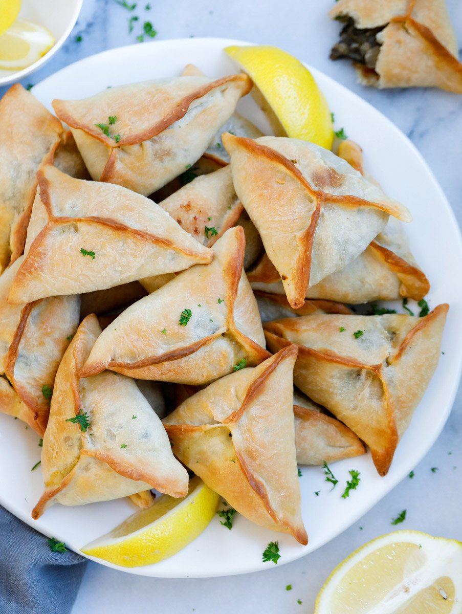 Lebanese Spinach Pie served on a plate with lemon wedges and garnished with parsley