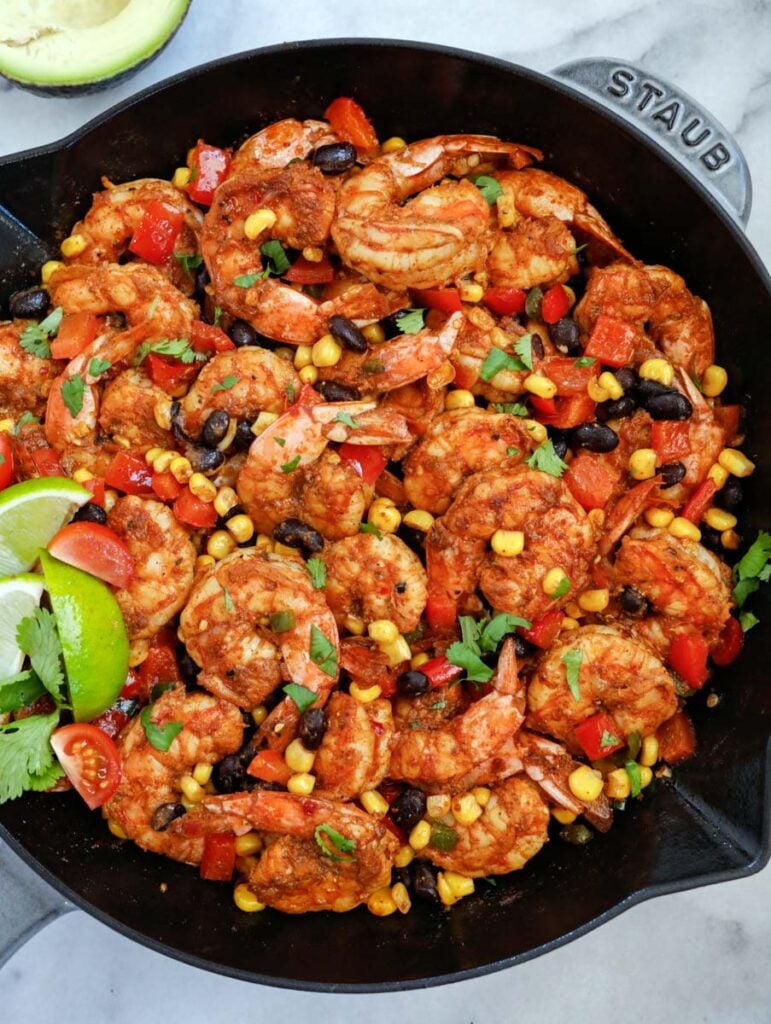 mexican shrimp in a skillet with lemon wedges and cilantro