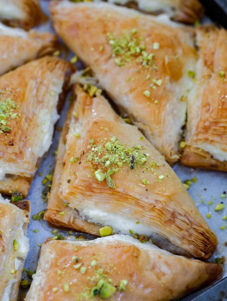 baked shaabiyet in a tray garnished with pistachio