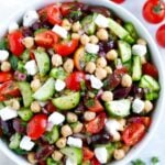 Bowl of chickpeas with cucumber, tomatoes, olives, feta, onion, and parsley.