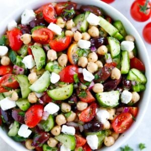 Bowl of chickpeas with cucumber, tomatoes, olives, feta, onion, and parsley.