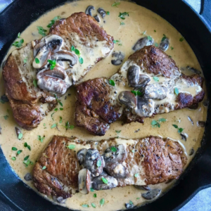 Seared steaks topped with mushrooms in a rich garlic cream sauce.