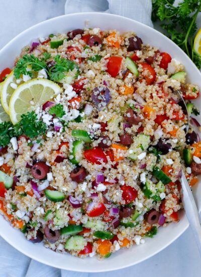 mediterranean quinoa salad served in a dish, dopped with feta cheese and lemon wedges