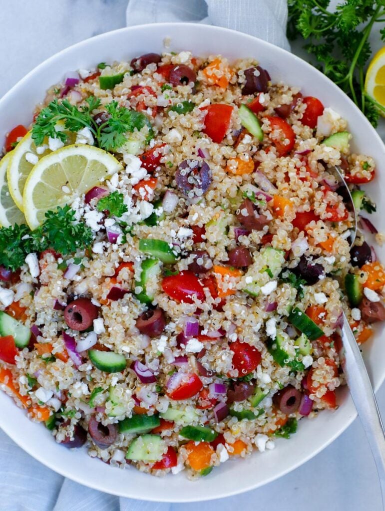 mediterranean quinoa salad served in a dish, dopped with feta cheese and lemon wedges