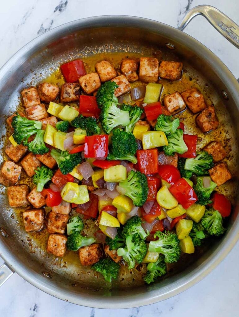 top down shot of salmon with vegetables in a skillet