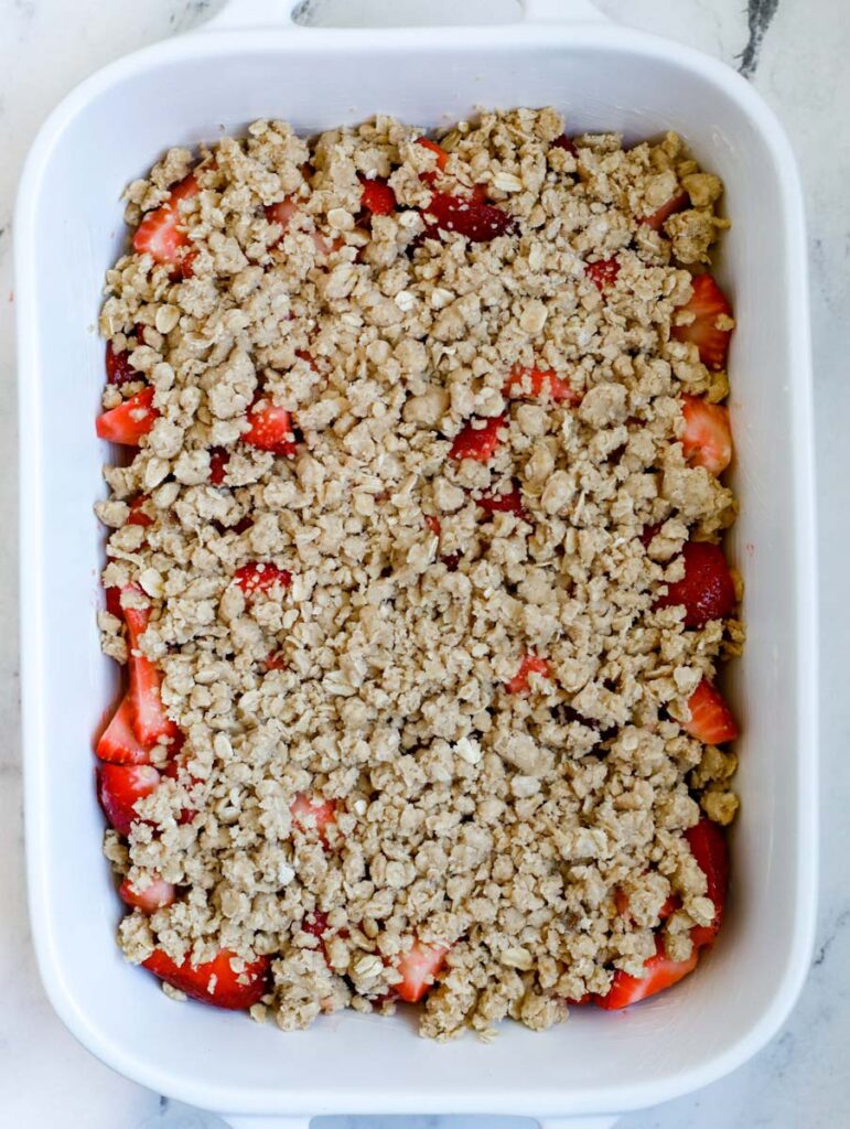 strawberry crisp uncooked in a baking dish