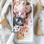 strawberry cheesecake ice cream in a pan with scoops of ice cream