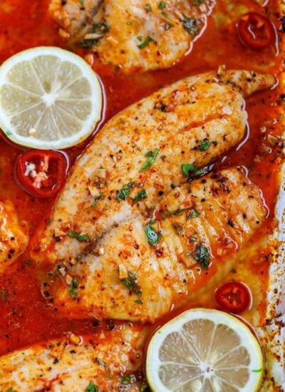 oven baked tilapia fish on a tray with lemon wedges