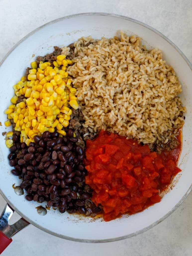 beans, tomatoes, rice and corn in a skillet.