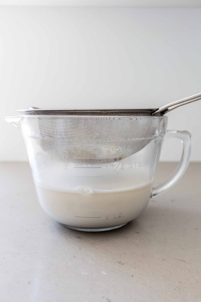 oat milk straining into a bowl
