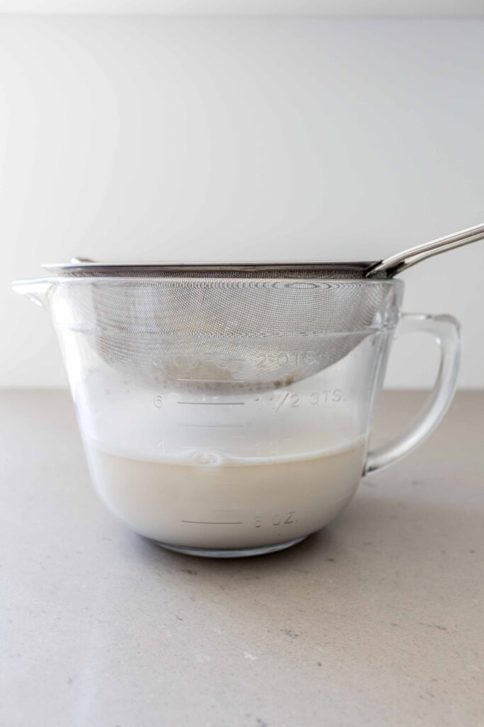 oat milk straining into a bowl