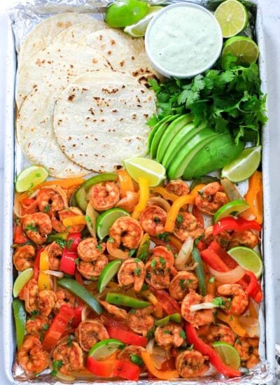 shrimp fajita in a sheet pan with tortilla, avocado and dressing