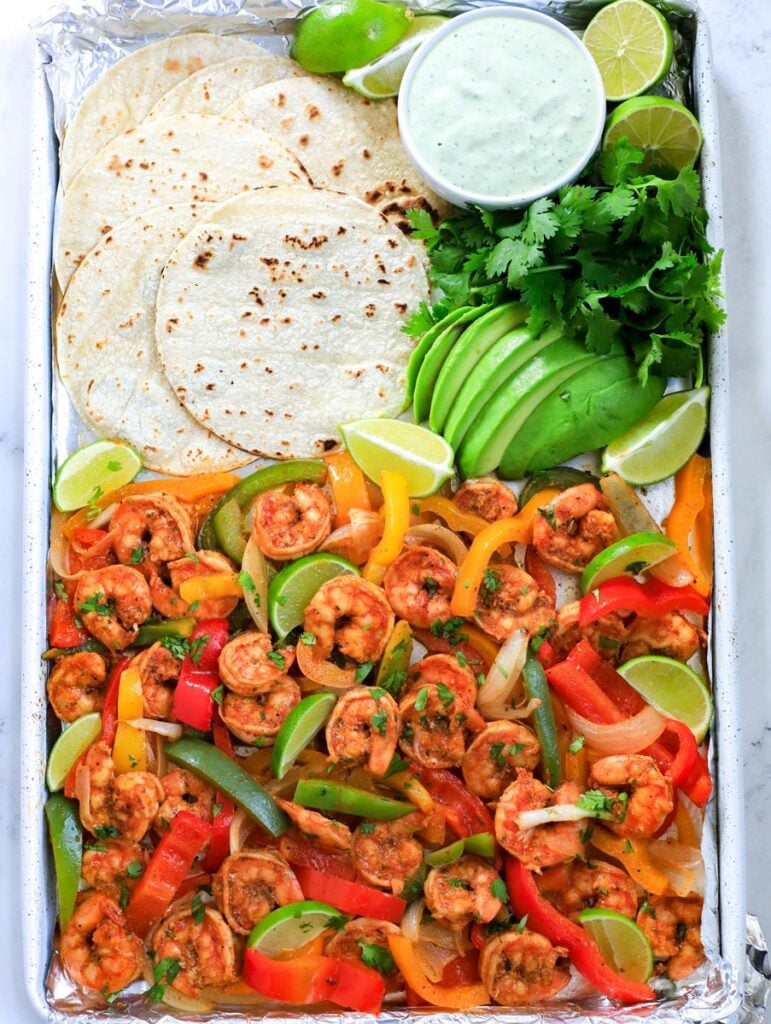 shrimp fajita in a sheet pan with tortilla, avocado and dressing