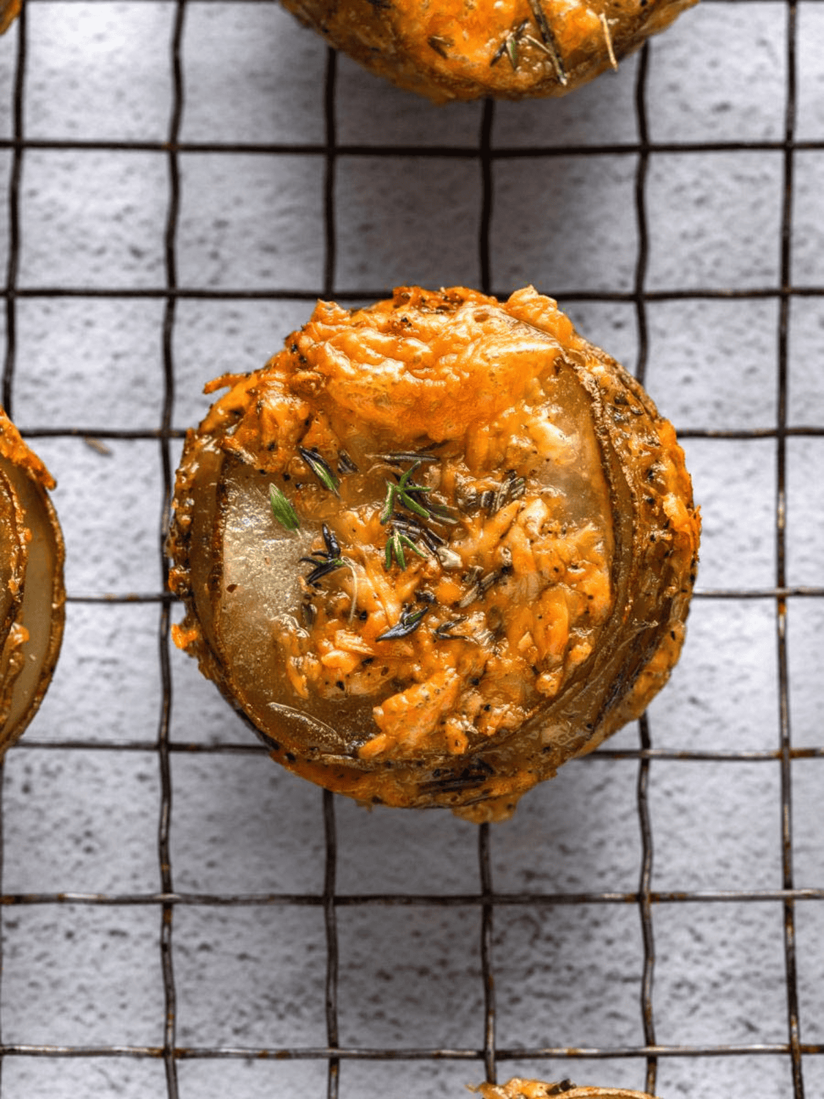 Cheesy Potato Stacks cooling on a wire rack with melted cheese and fresh herbs.