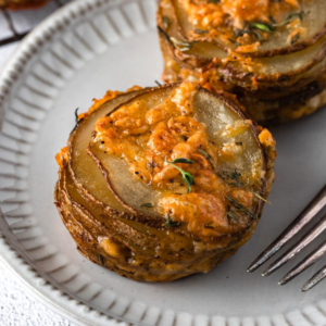 Cheesy stacked potatoes on a plate.