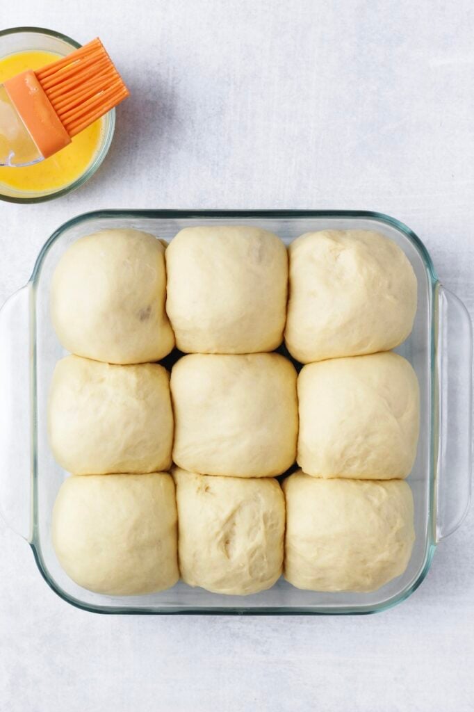 Process photo showing dinner rolls proofing a second time in a baking dish.