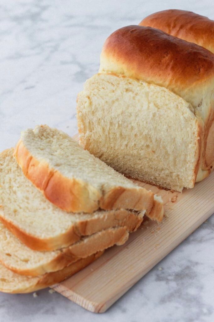 Sandwich loaf being sliced into four slices.