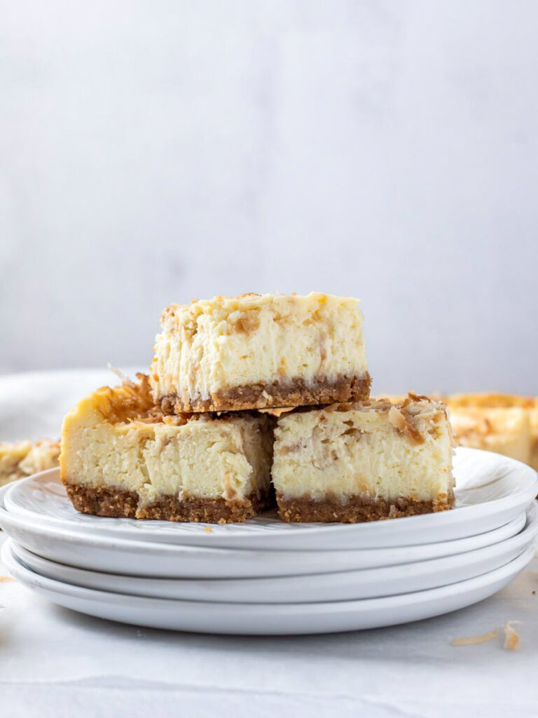 coconut cheesecake bars stacked on a plate