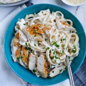 Sliced golden chicken over fettuccine in Parmesan cream sauce with fresh parsley.
