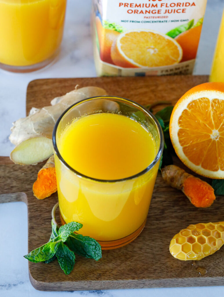 orange booster drink surrounded with ingredients used to make it