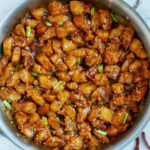 Sticky glazed chicken with dried chilies, green onions, and sesame seeds.