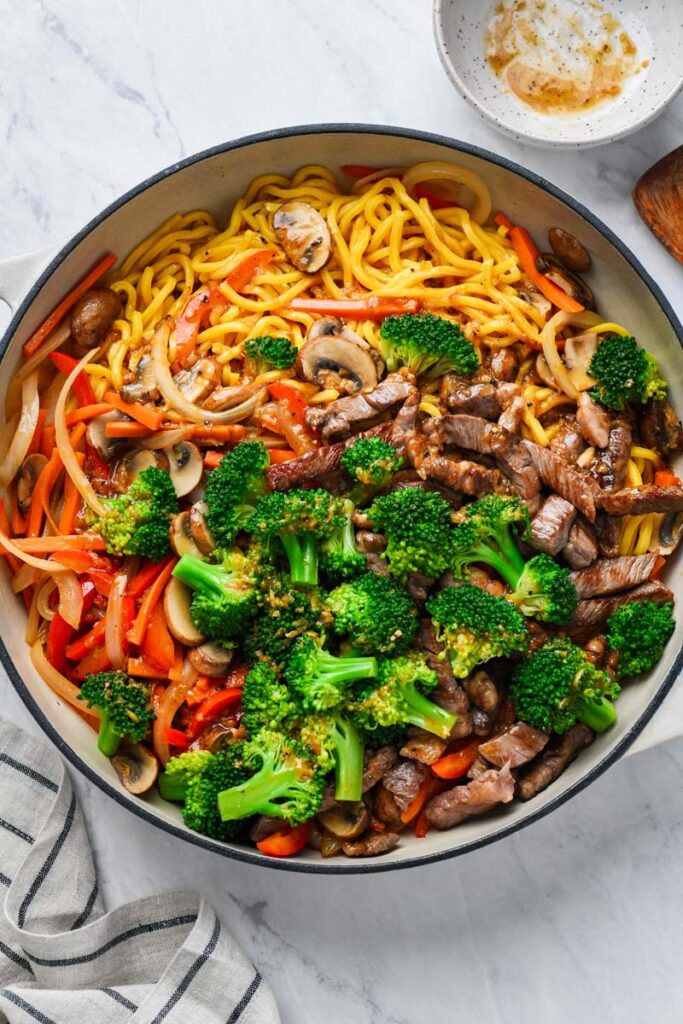 beef lo mein ingredients in a skillet ready to be mixed with sauce