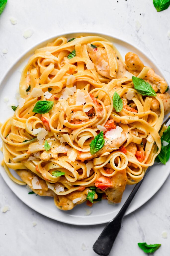 tomato basil pasta served on a white plate with a fork on the side