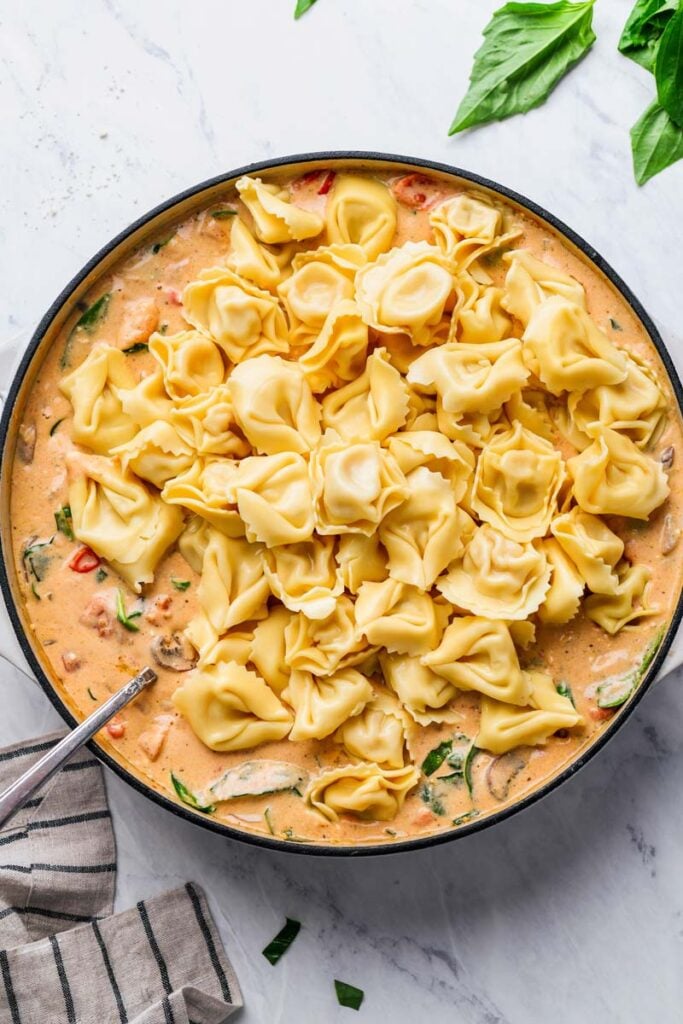 tortellini pasta placed in the skillet over the creamy sauce