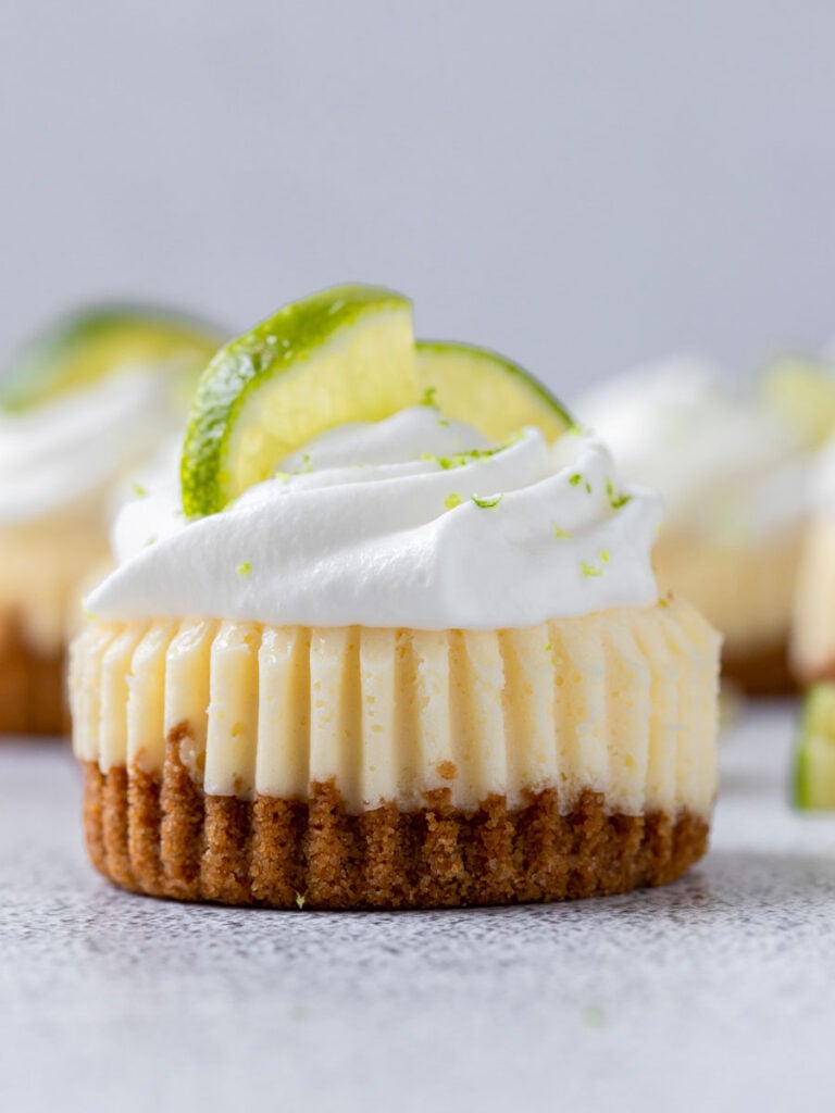 close up shot of mini key lime cupcake with whipped cream and lemon slices on top