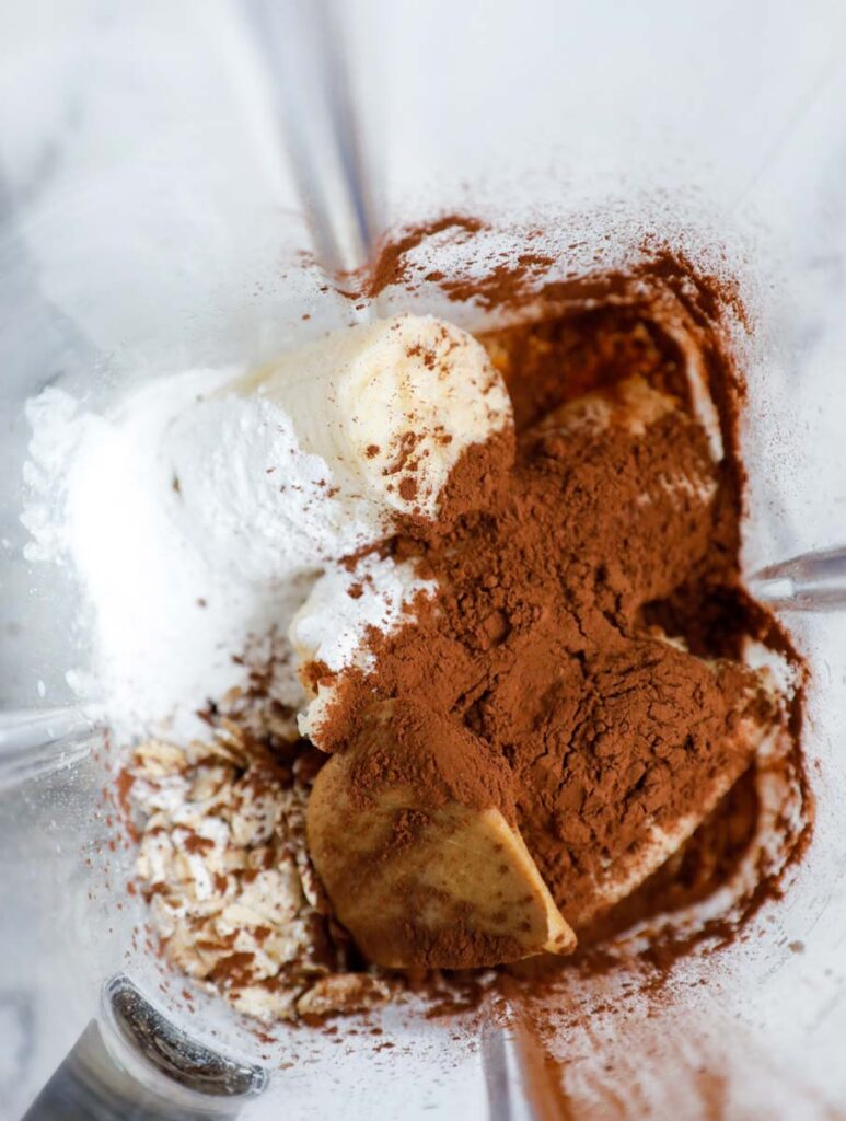 Ingredients for peanut butter chocolate baked oats inside of a blender.