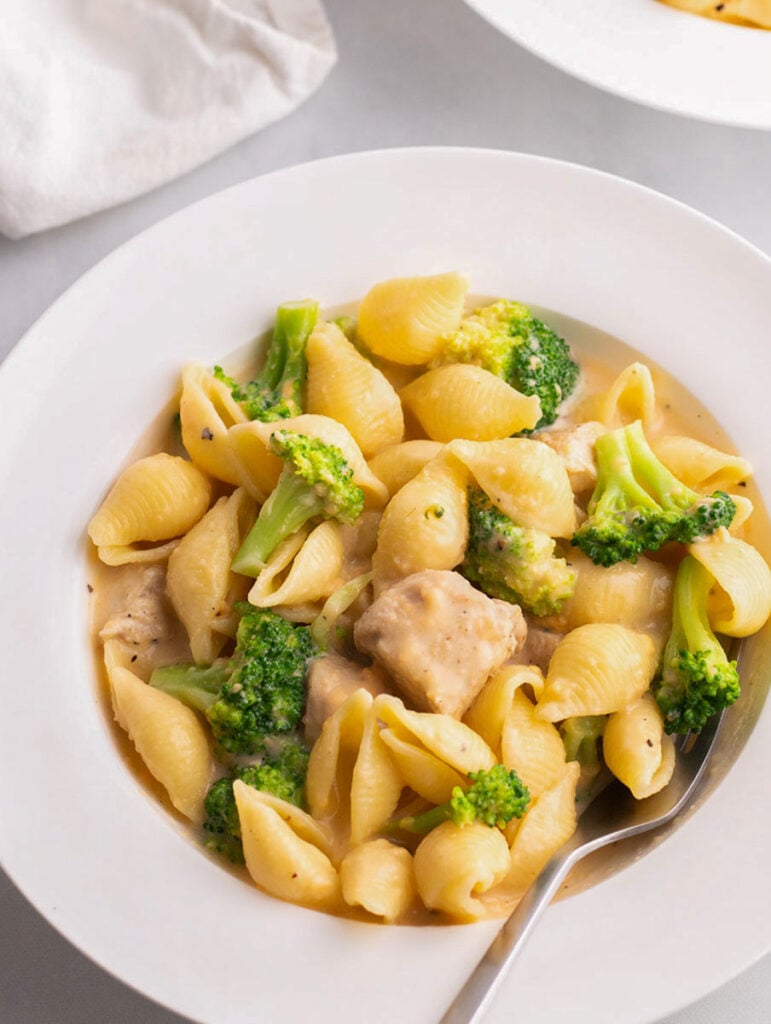 creamy broccoli mac and cheese in a white place with a fork