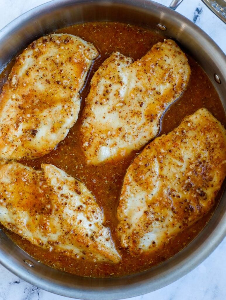 Adding chicken breasts to honey mustard sauce.