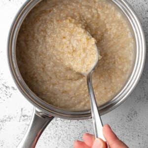 cooked oatmeal in a pot with a spoon scooping some oatmeal