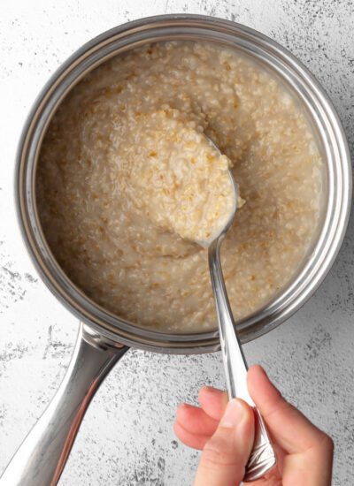 cooked oatmeal in a pot with a spoon scooping some oatmeal