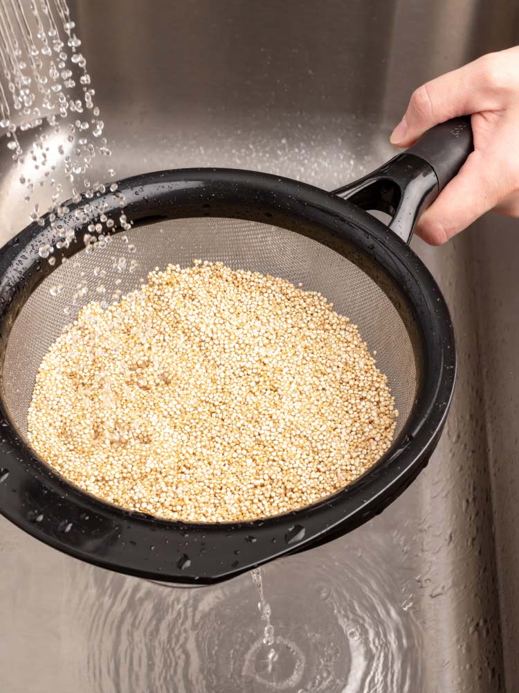 quinoa being washed in a strainer