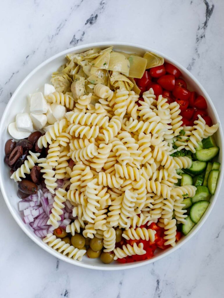 Ingredients for a pasta salad in a bowl.