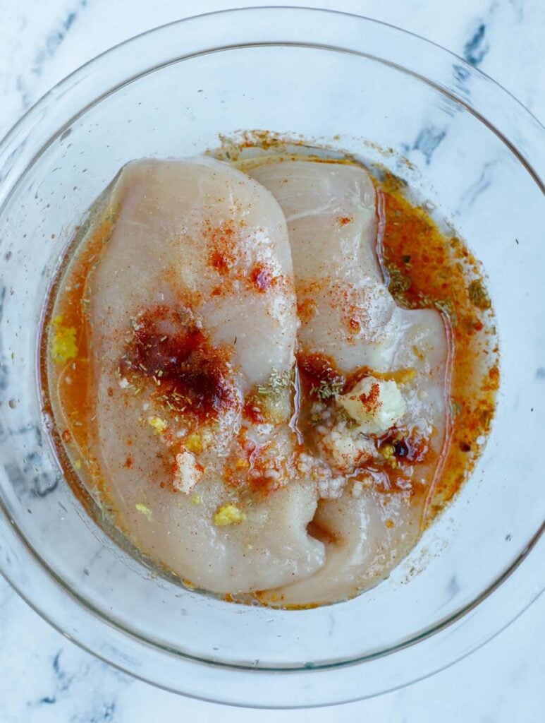 A bowl of chicken breasts with marinate.