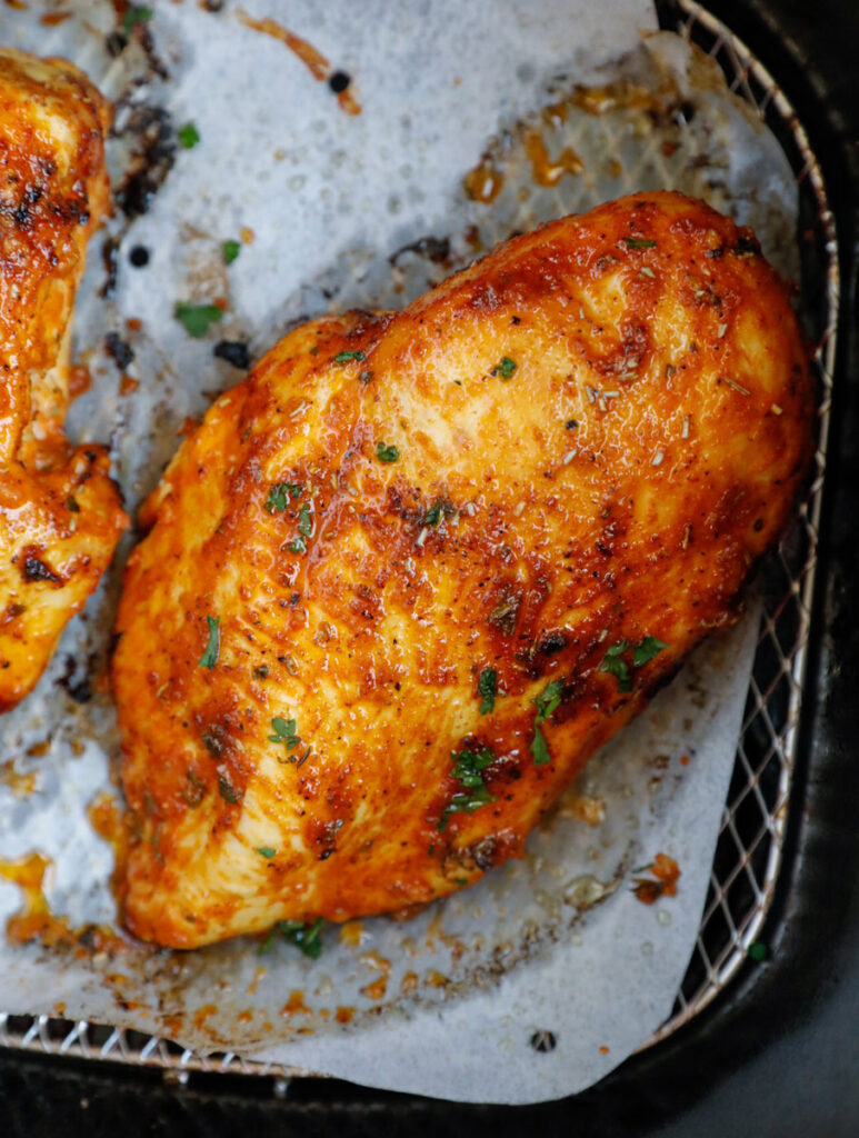 air fried chicken breasts in an air fryer basket.