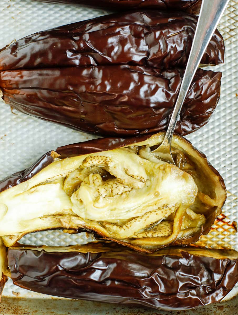 roasted eggplant flesh being scooped out with the spoon