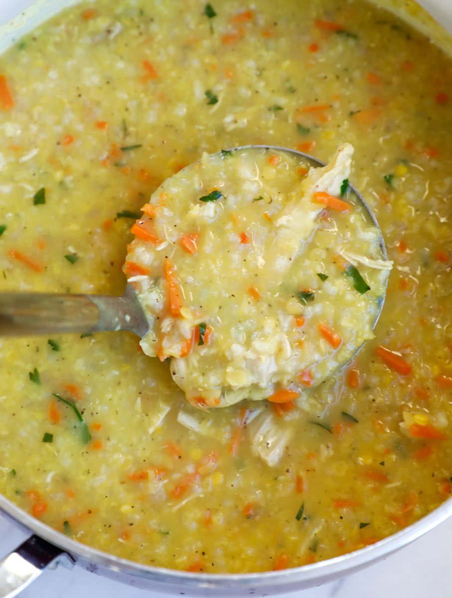 Ladle lifting up chicken lentil rice soup.