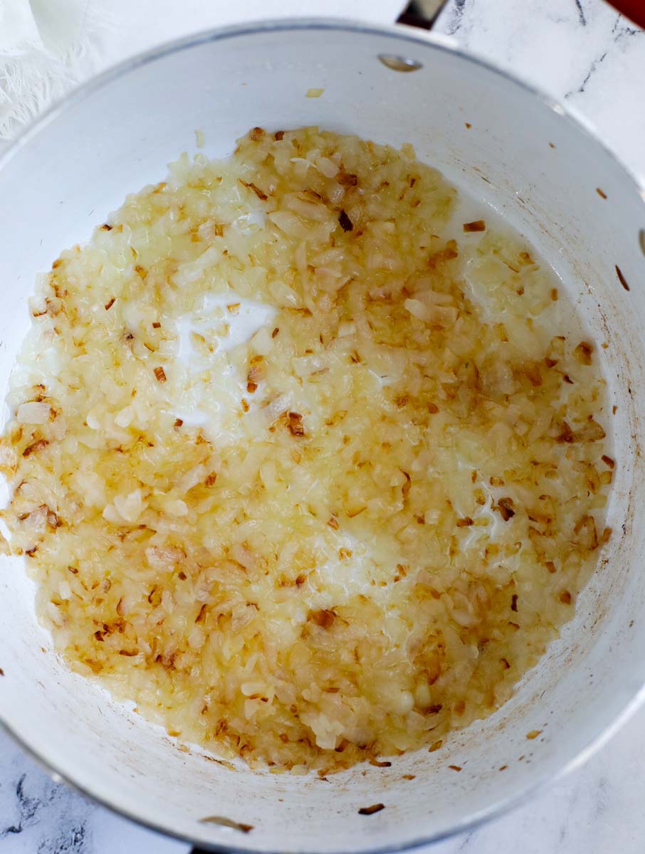 Onions being sautéed in a pot.