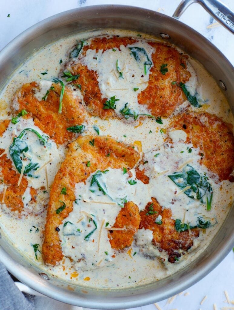 Overhead view of creamy parmesan chicken breasts inside of a pan.
