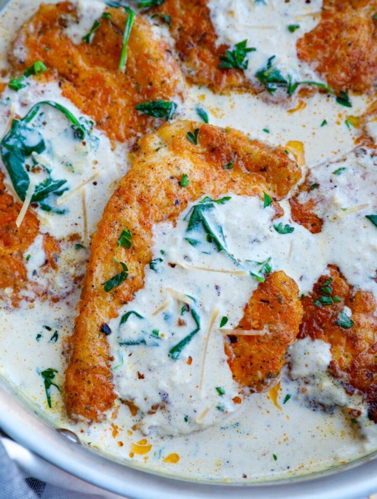 Close up of a creamy parmesan chicken breast in a pan.
