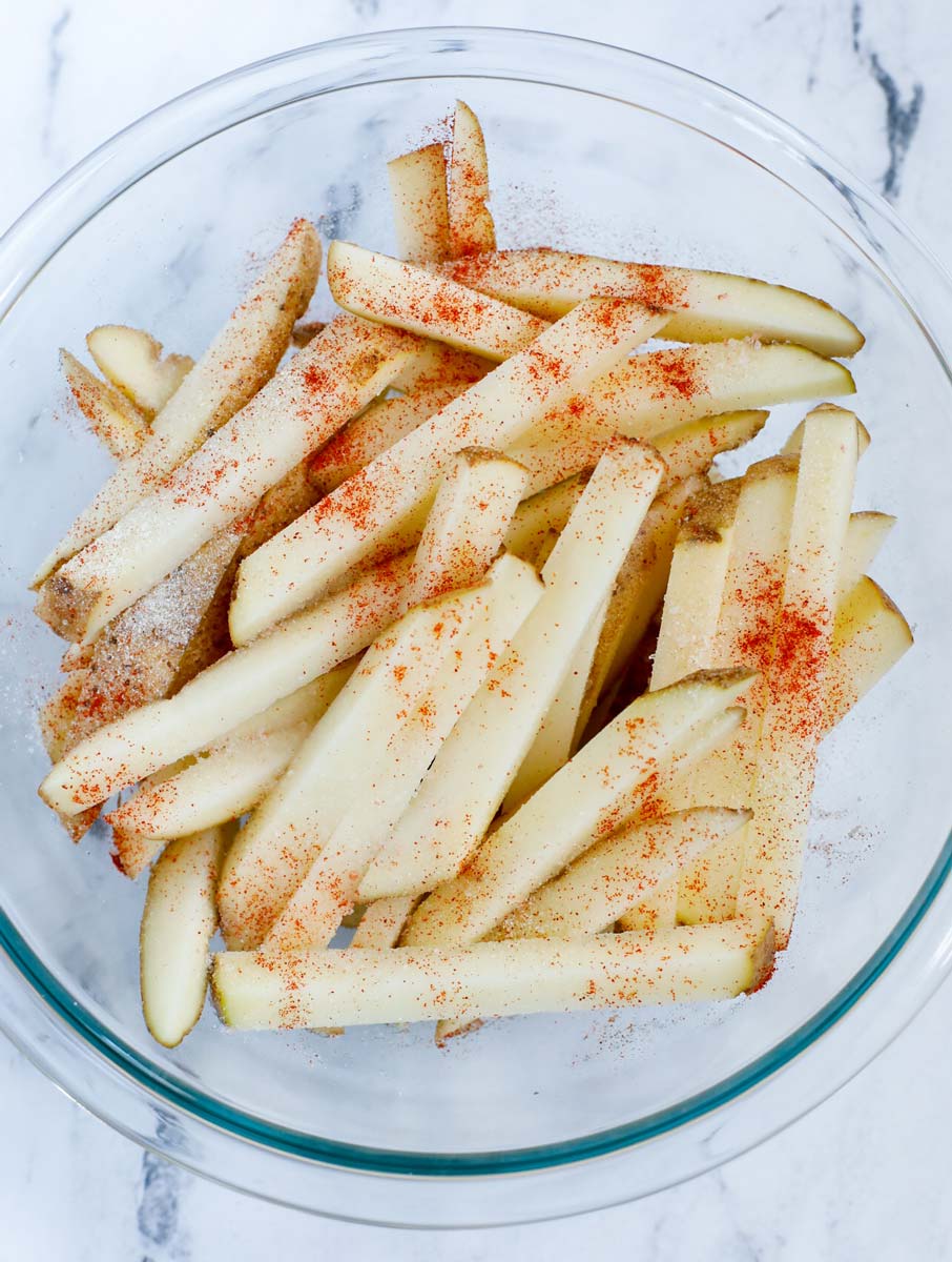 Seasoning hand cut french fries.