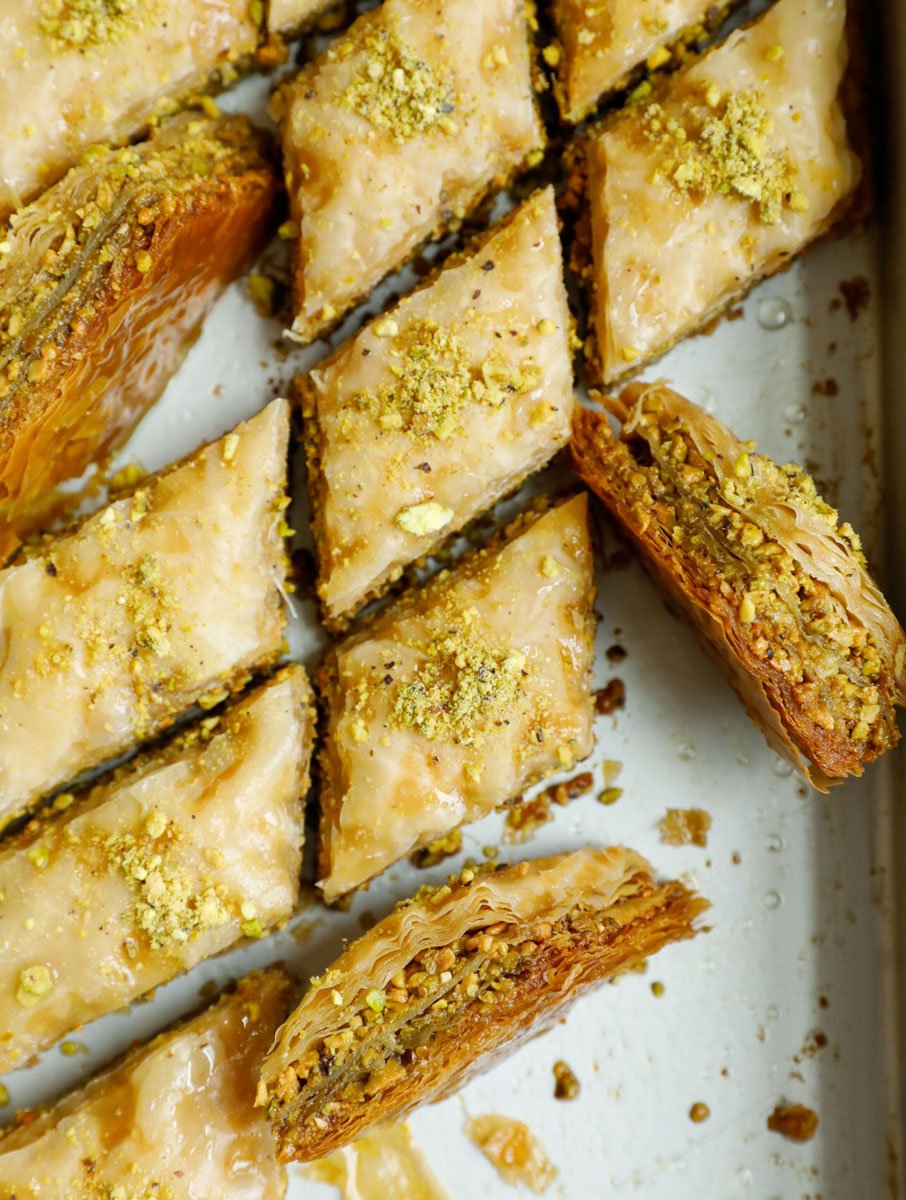 Servings of pistachio baklava being turned around from the pan.