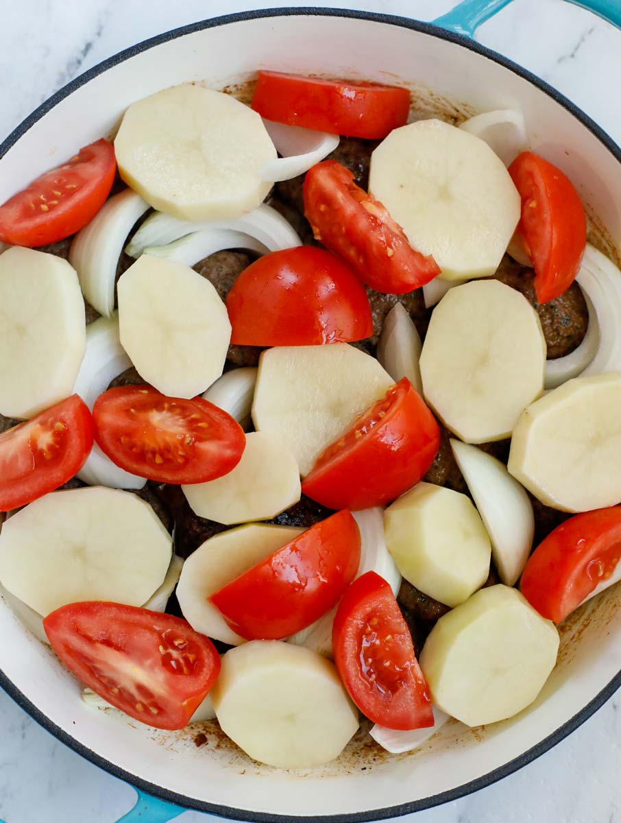 Kafta, potatoes, tomatoes, and onion in a pot.