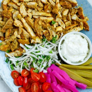 A platter of chicken shawarma with dip and sides.