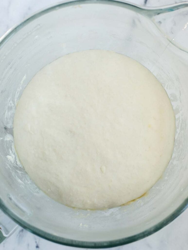 top down shot of the dough in a bowl after rising