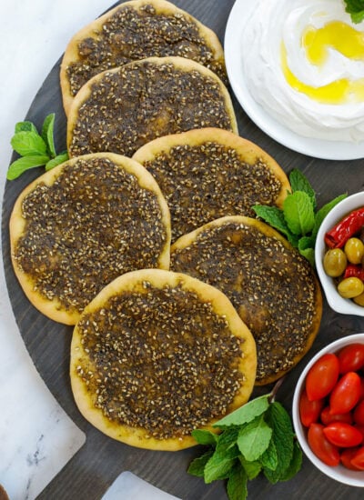 top down shot of the zaatar manakeesh on a dark board served with labneh